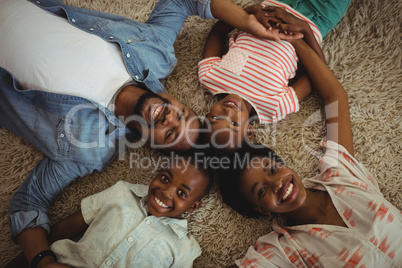Portrait of happy parents and kids lying on rug