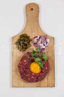 Beef patty, onions and olives on wooden board