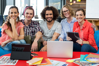 Smiling graphic designers sitting in office with laptop and digital tablet on table