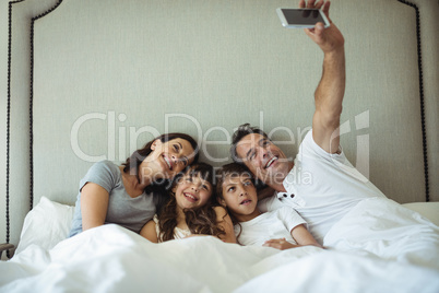 Parents and kids taking a selfie on bed