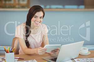 Portrait of beautiful Executive sitting at desk and using digital tablet