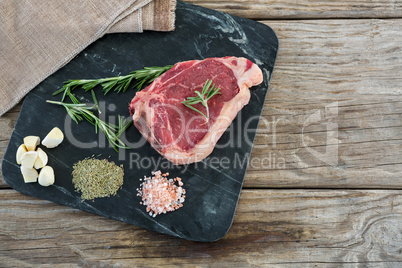 Sirloin chop and ingredients on slate board against wooden background