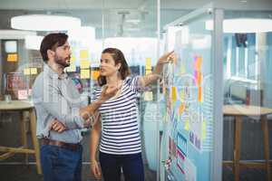 Male and female business executives discussing over whiteboard