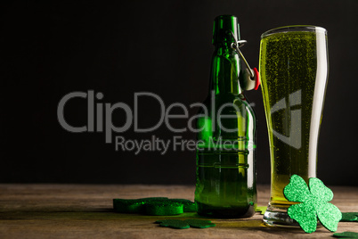 Glass of green beer, beer bottle and shamrocks for St Patricks Day