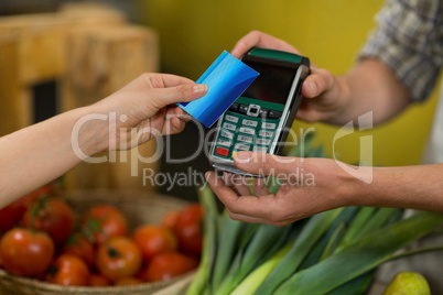 Woman making a payment by using NFC technology in the grocery store