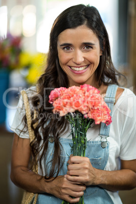 Smiling woman holding a bunch of flowers at florist shop