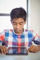 Schoolboy using digital tablet at desk