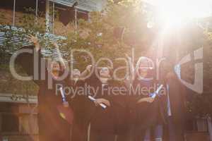 Successful graduate school kids throwing mortarboard in air in campus