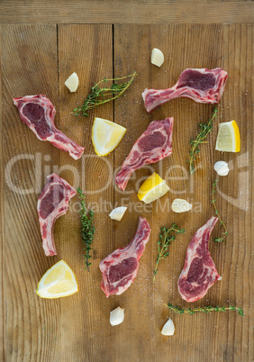 Rib chops, herbs and lemon against wooden background
