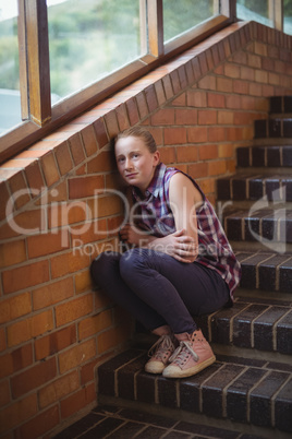 Sad schoolgirl sitting alone on staircase