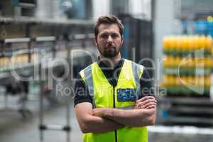 Factory worker standing with arms crossed in factory