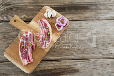 Sirloin chop, onions and garlic on wooden tray