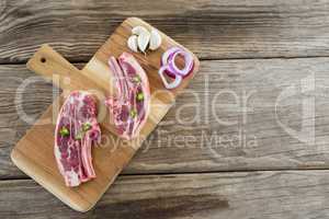 Sirloin chop, onions and garlic on wooden tray