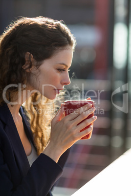 Businesswoman drinking cup of coffee in office