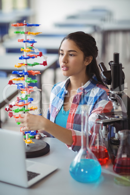 Attentive schoolgirl experimenting molecule model in laboratory