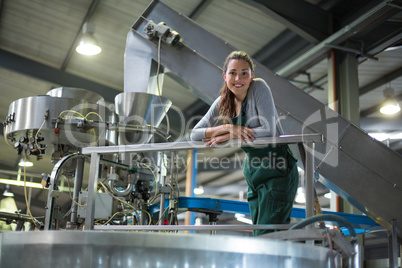 Female factory worker standing near a storage tank