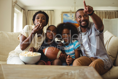 Parents and kids having fun while watching television in living room