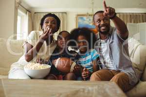 Parents and kids having fun while watching television in living room