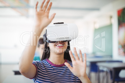 Schoolgirl using virtual reality headset in classroom