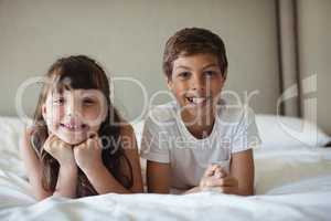 Siblings smiling in bed