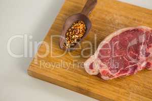 Sirloin chop and spices in wooden spoon on wooden board