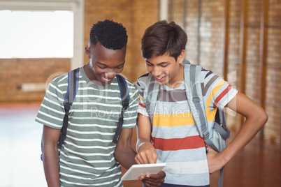 Happy schoolboys using digital tablet in campus