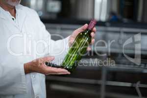 Factory worker examining a bottle in factory