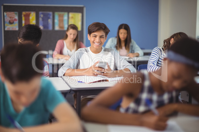 Student holding mobile phone in classroom