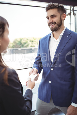 Businesswoman giving visiting card to businessman