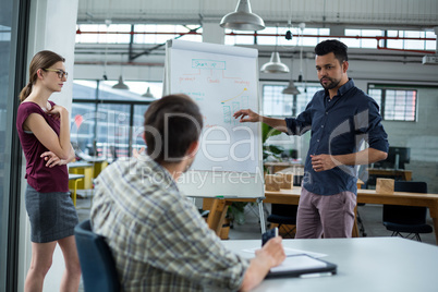 Business executives discussing over flip chart during meeting