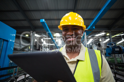 Smiling factory worker using a digital tablet in the factory