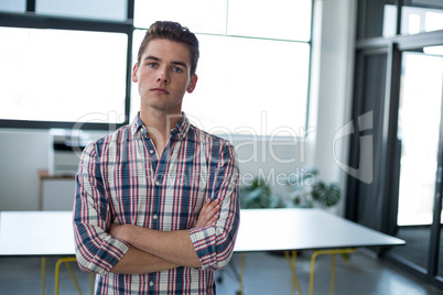 Sad business executive standing with arms crossed in office