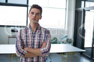 Sad business executive standing with arms crossed in office