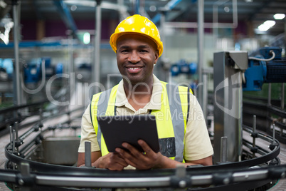 Smiling factory worker using a digital tablet in the factory