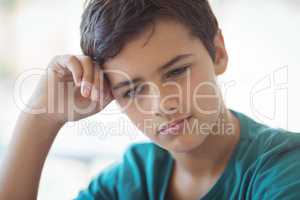 Thoughtful schoolboy sitting in classroom