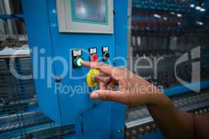 Hands of factory worker pressing a green button on the control board