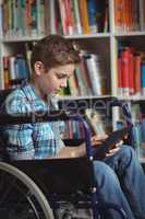 Disabled schoolboy using digital tablet in library