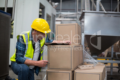 Male factory worker counting cardboard boxes