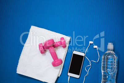 Mobile phone, water bottle, towel and dumbbell kept on exercise mat