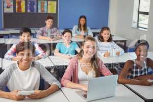 Students with digital tablet and laptop in classroom