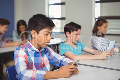 Students with digital tablet and mobile phone in classroom