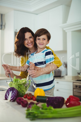 Portrait of mother and son mixing the salad in kitchen