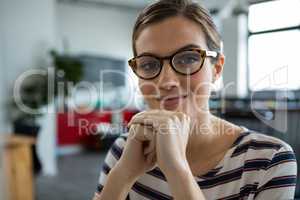 Smiling female graphic designer in spectacles at creative office