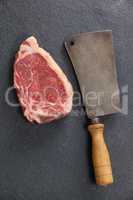 Sirloin chop and cleaver against black background