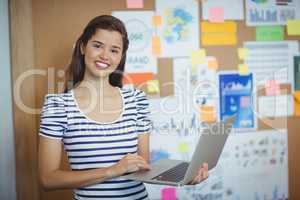 Female executive holding laptop in office