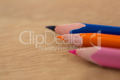 Colored pencils arranged in diagonal line on wooden background