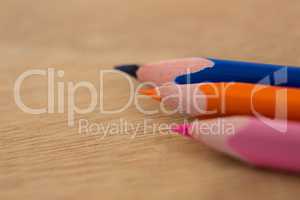 Colored pencils arranged in diagonal line on wooden background