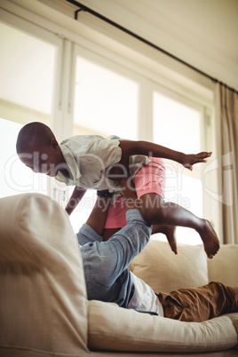 Father playing with son on sofa in living room