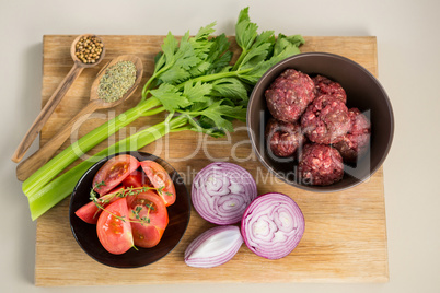 Minced meat and ingredients on wooden board