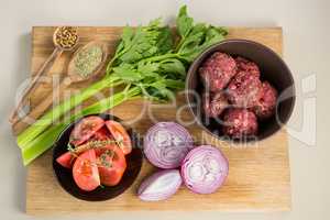 Minced meat and ingredients on wooden board